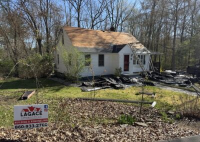 Lagace Construction replacing roof on white home in Andover, CT with visible branding sign and stripped shingles